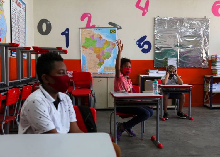 Criança levanta a mão ao lado de outros alunos em sala de aula da escola Thomaz Rodrigues Alckmin, no primeiro dia de retorno das escolas do estado de São Paulo para atividades extracurriculares em meio ao surto de coronavírus (COVID-19) em São Paulo, Brasil Outubro 7, 2020. REUTERS / Amanda Perobelli